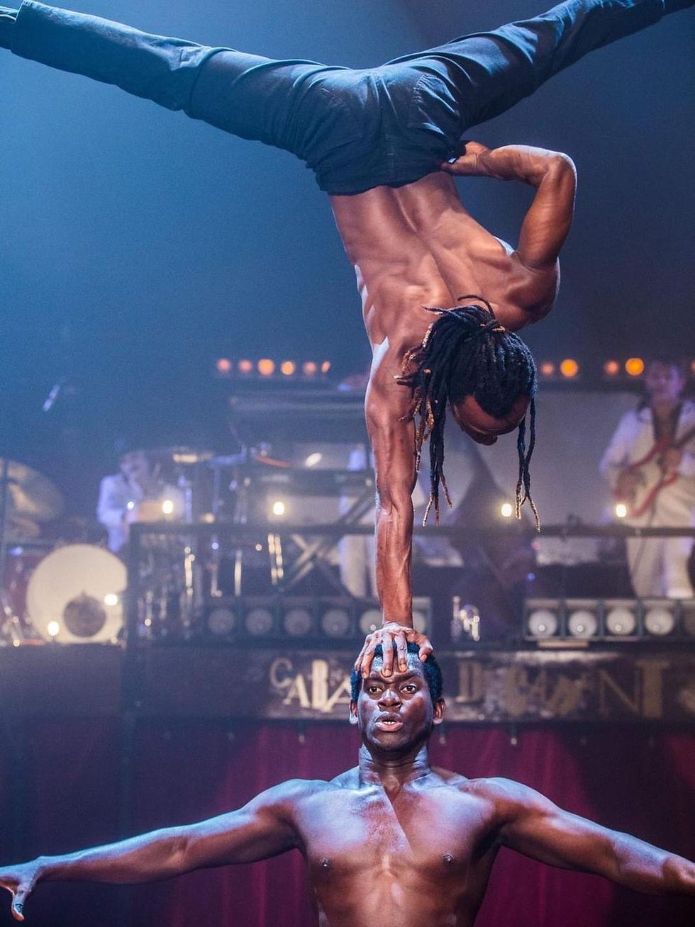 Two Afrikan Warriors performers in a handstand balance